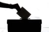 voter putting ballot in box